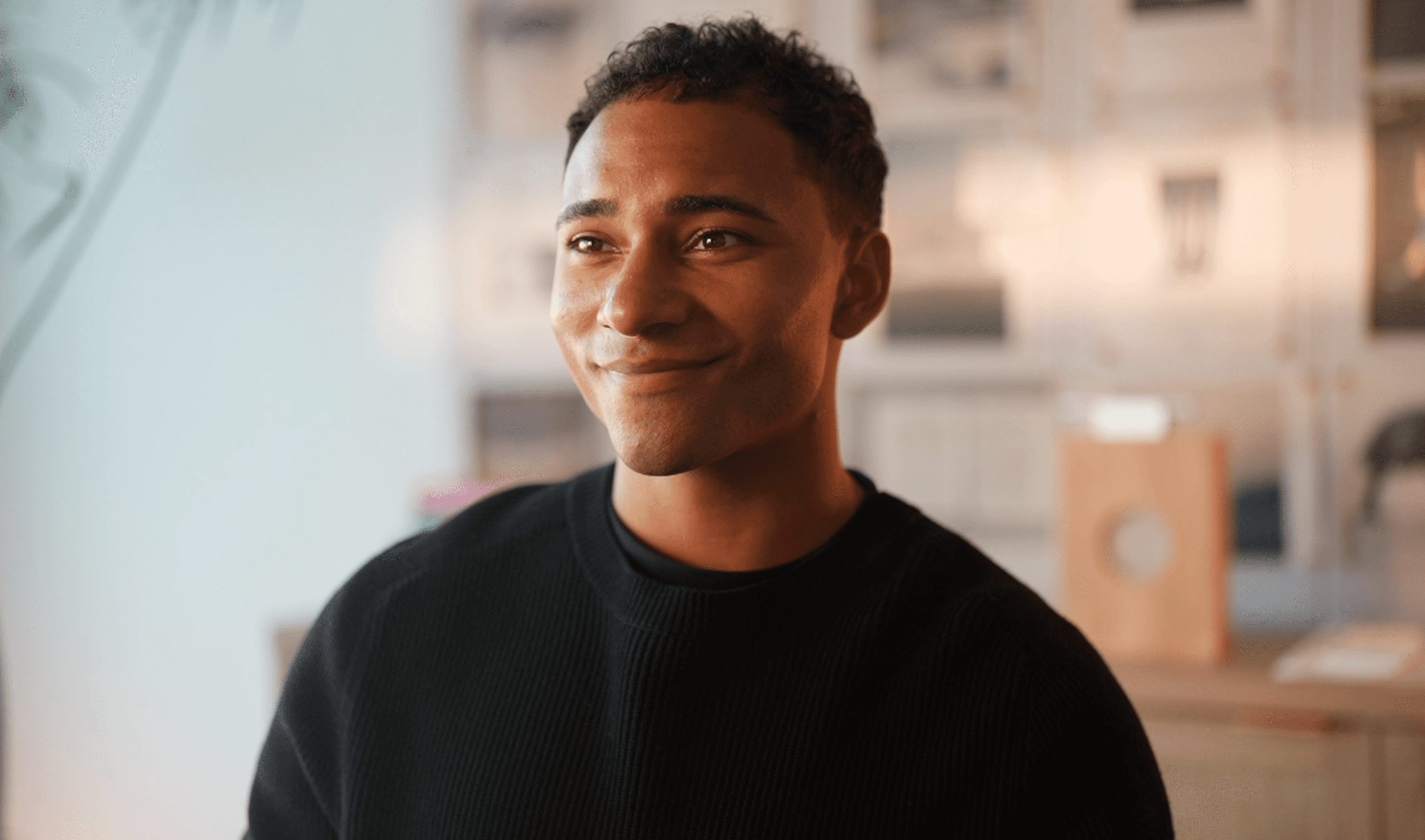 Portrait of Domenic Ashburn smiling in warm interior light.
