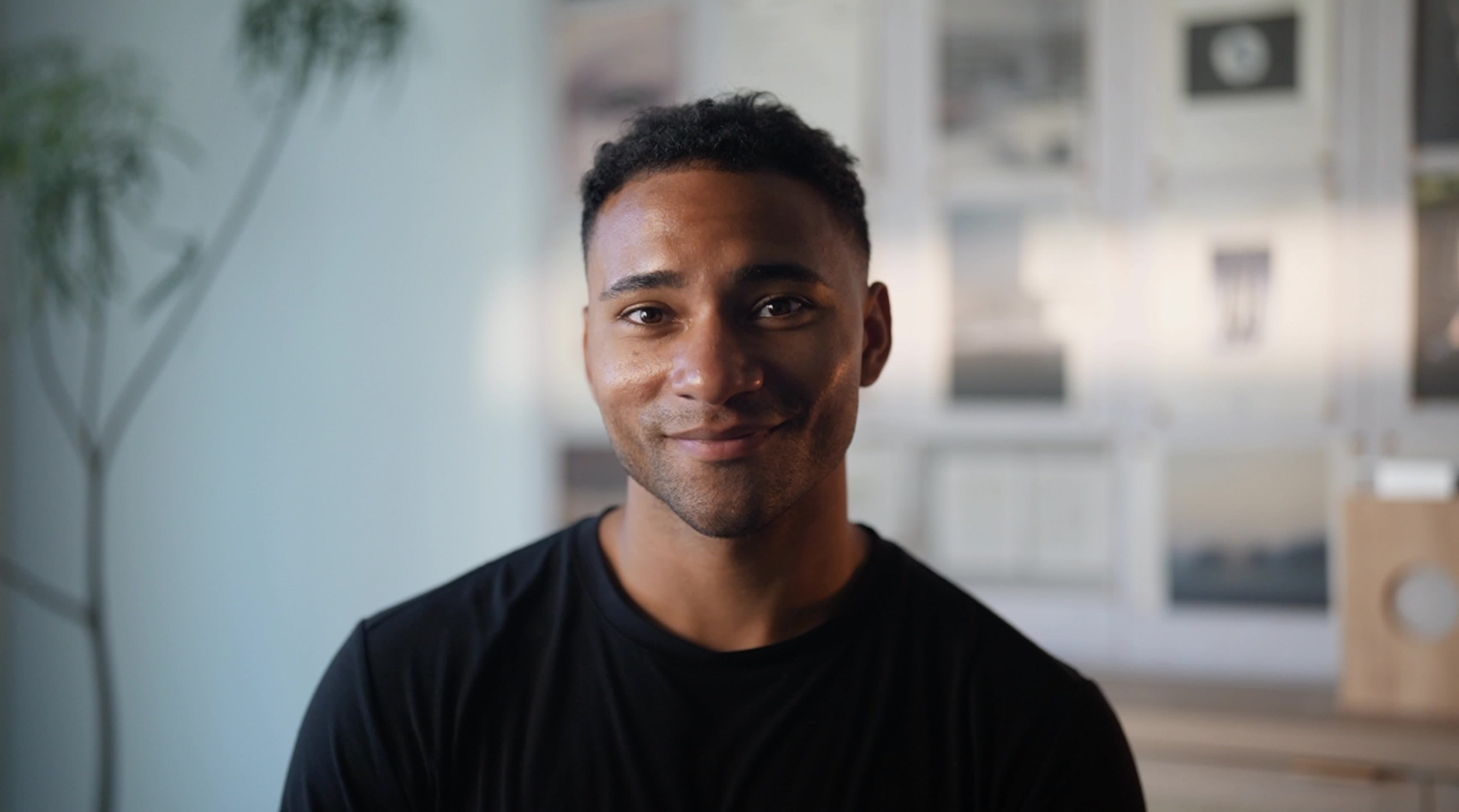 Portrait of Domenic Ashburn smiling in warm interior light.